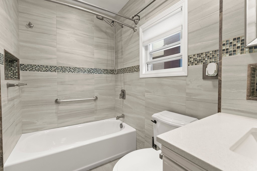 A white bathroom with a tub, toilet and sink.