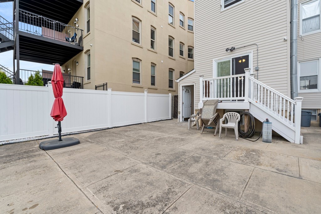A patio with a red umbrella and white fence.