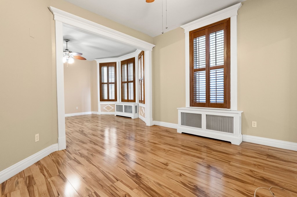 A room with wooden floors and a window with blinds.