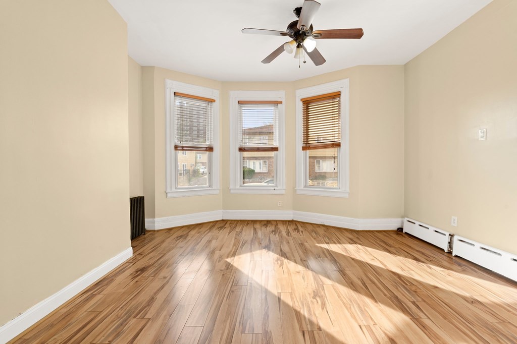 A room with a ceiling fan and wooden flooring.