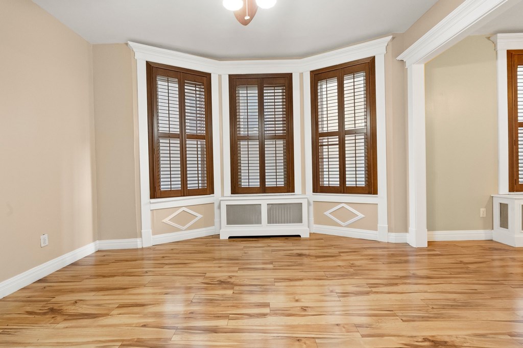 A room with wooden floors and a window with blinds.
