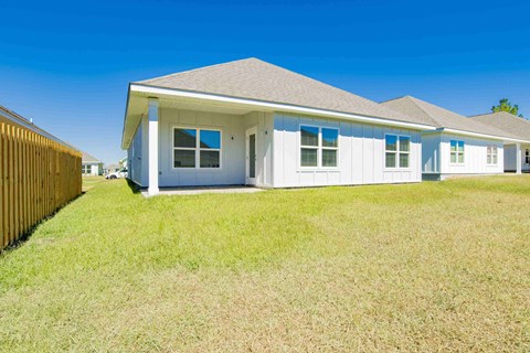 A white house with a brown fence in front of it.