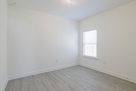 A room with a window and wooden flooring.