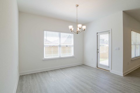 A room with a chandelier, a window with blinds, and a door.