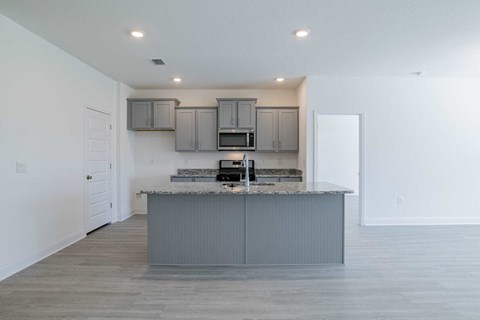 A kitchen with a marble countertop and grey cabinets.
