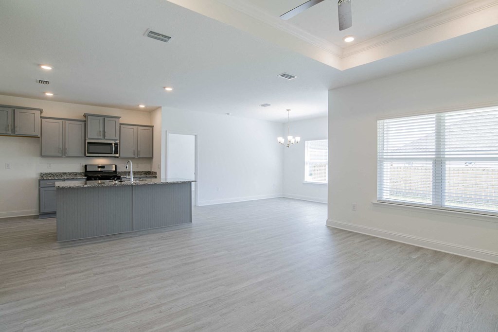 A spacious kitchen with a bar counter and a window with blinds.