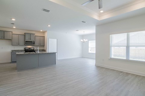 A spacious kitchen with a bar counter and a window with blinds.