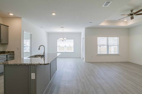 A spacious kitchen with a granite countertop and a ceiling fan.