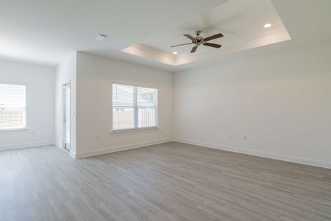 A spacious room with a ceiling fan and lighting fixture.