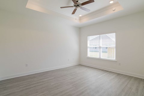 A room with a ceiling fan and a window with blinds.