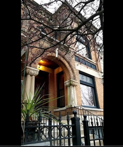 A brick building with a black iron fence in front.