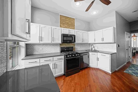 A modern kitchen with white cabinets and a black stove top oven.