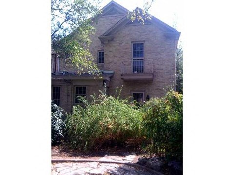 a brick house with bushes in front of it