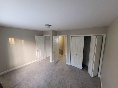 a bedroom with three closets and a carpeted floor