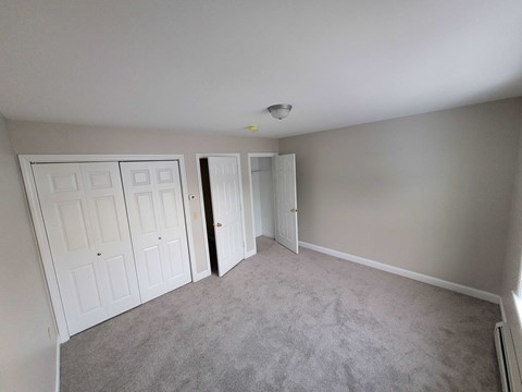 a bedroom with three closets and a carpeted floor