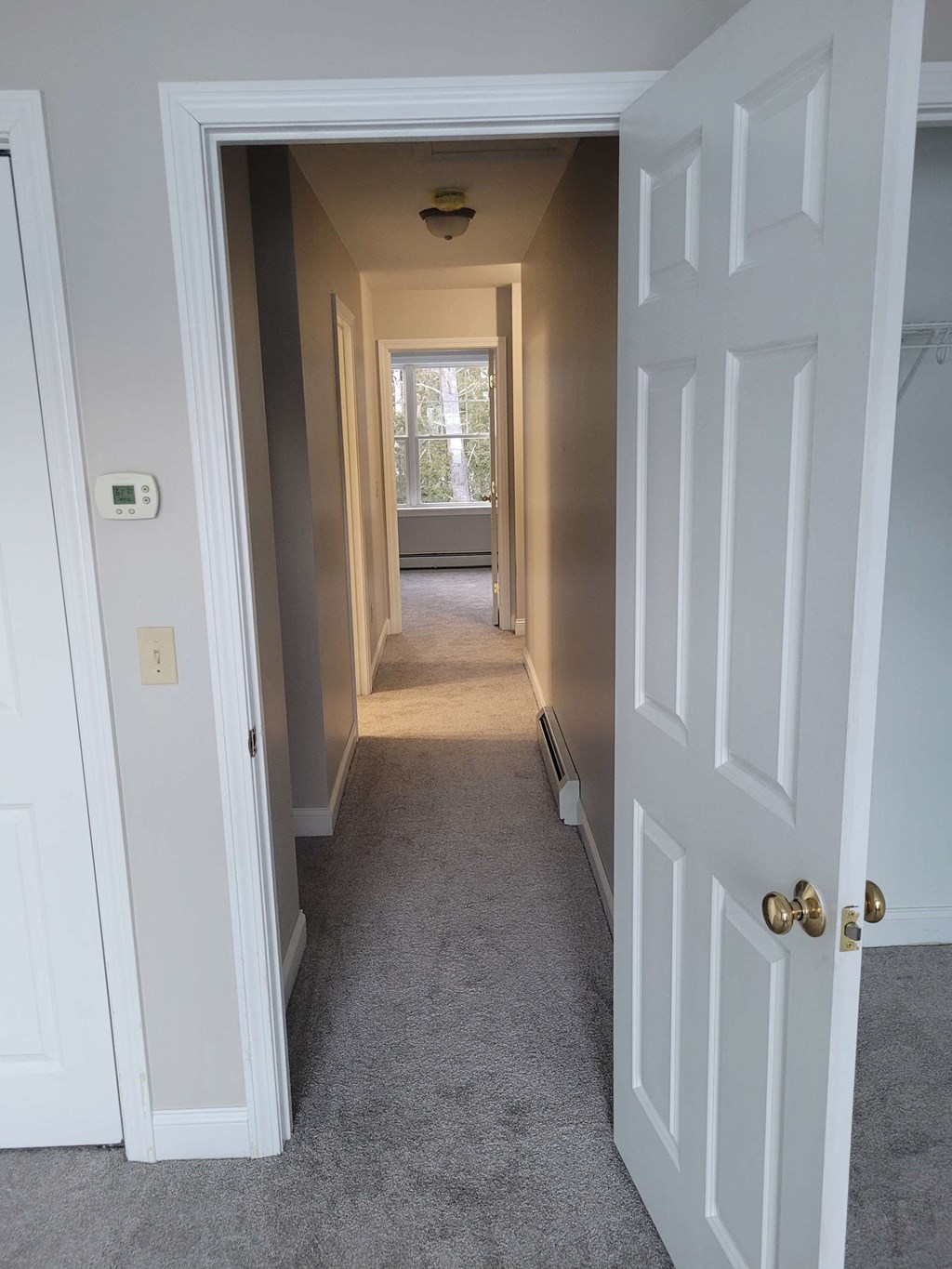 a long hallway with white doors and a carpeted floor