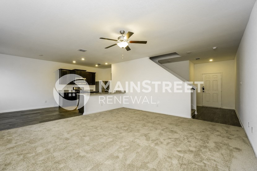 a renovated living room with a white wall and a ceiling fan