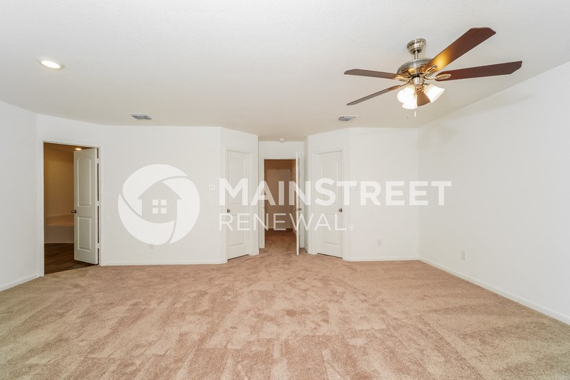 a living room with white walls and a ceiling fan