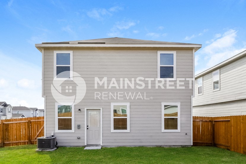 a renovated house with a yard in front of a wooden fence