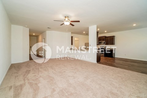 a large living room with a ceiling fan and a rug