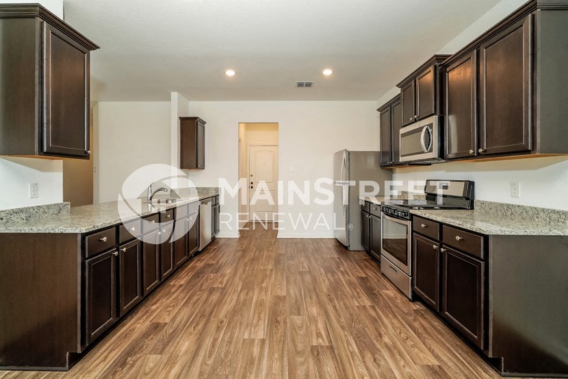 a kitchen with wood flooring and counters and stainless steel appliances