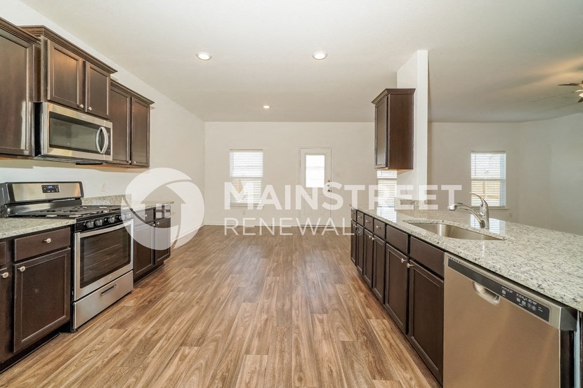 a renovated kitchen with granite countertops and stainless steel appliances