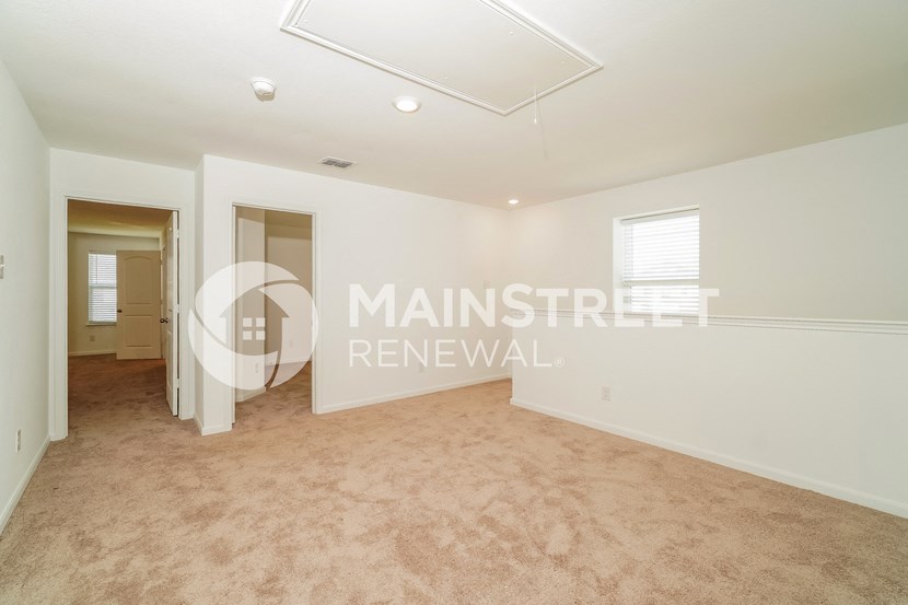 a living room with a white carpet and a door to a hallway