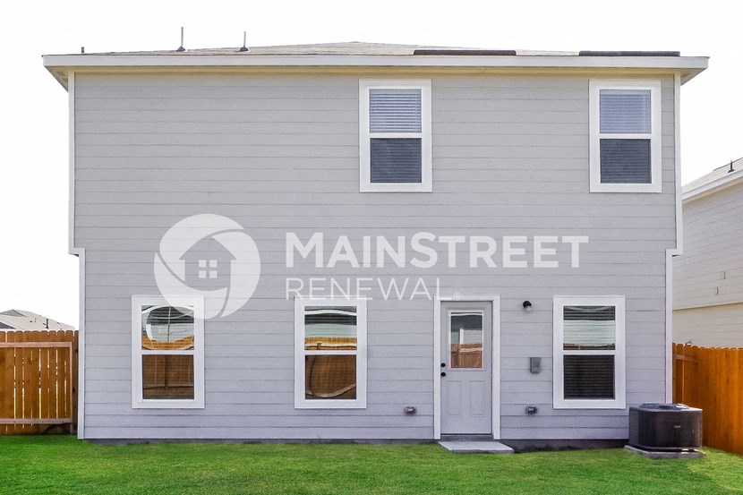 front view of a gray house with white siding and green grass
