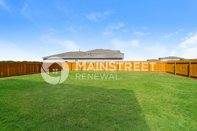 a backyard with a lawn and a wooden fence