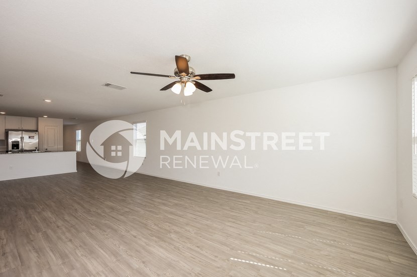 a living room with a white wall and a ceiling fan