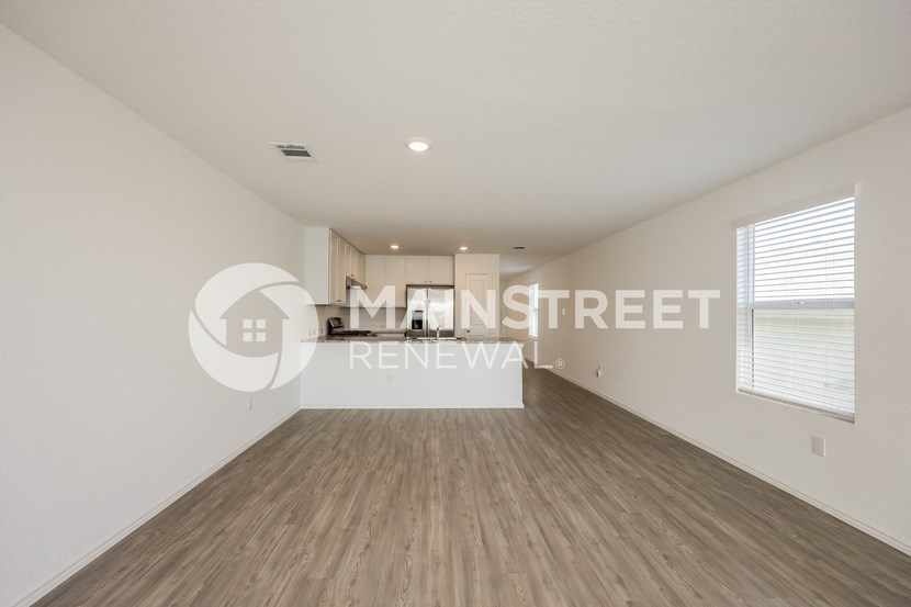a room with a hard wood floor and white walls and a large window