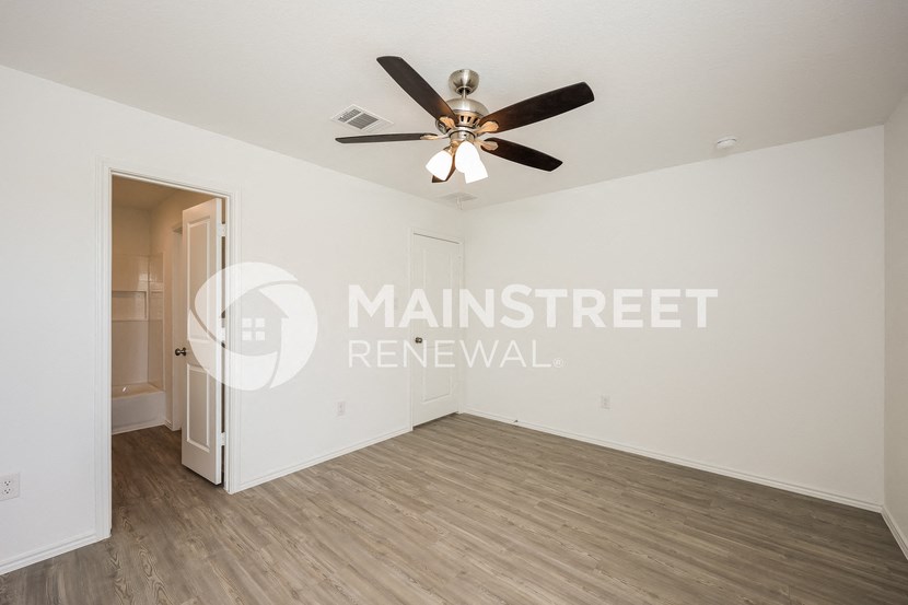 a living room with a ceiling fan and a door to a bathroom