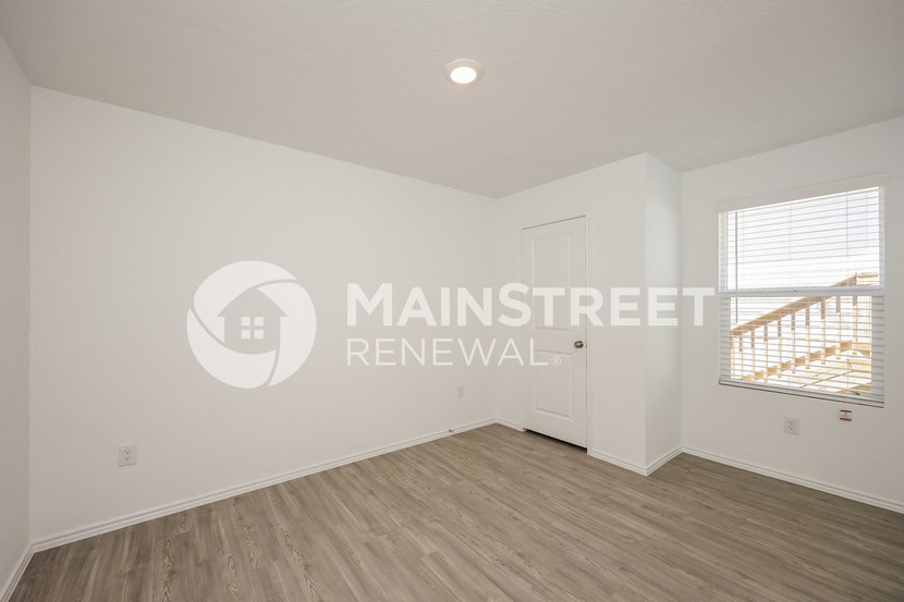 a bedroom with a hardwood floor and a door to a balcony