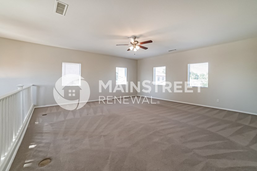 a living room with a ceiling fan and a carpeted floor