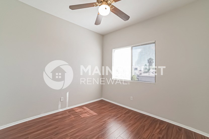 a bedroom with a hardwood floor and a ceiling fan