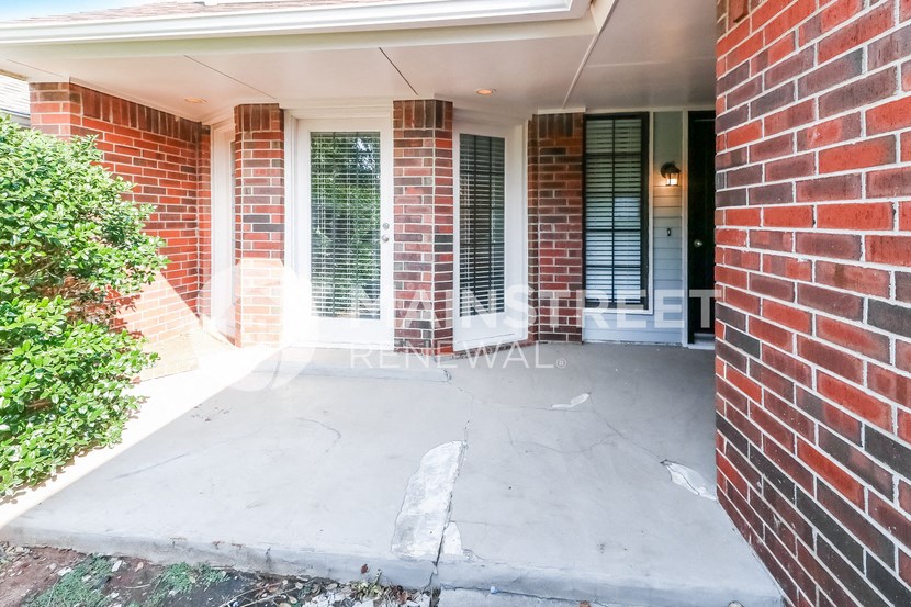 an empty porch of a brick house with a brick wall