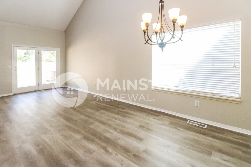 a renovated living room with hardwood floors and a chandelier