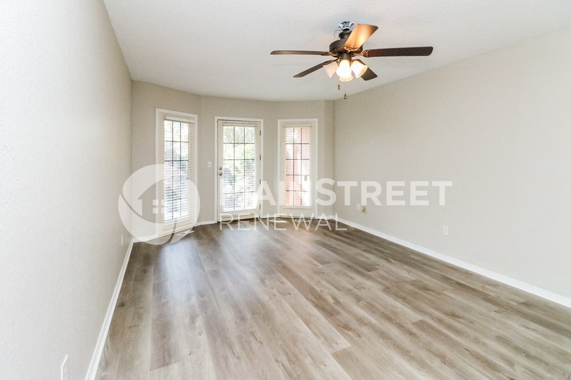 a renovated living room with hardwood floors and a ceiling fan
