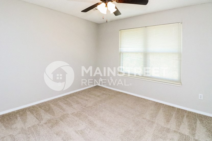 a bedroom with a ceiling fan and a large window