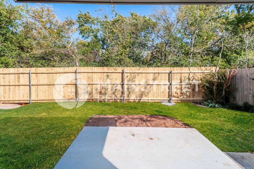 a backyard with a wooden fence and green grass and a lawn