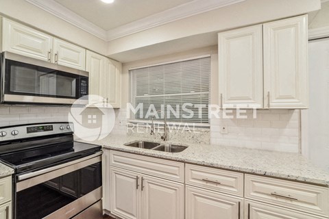 a renovated kitchen with white cabinets and granite counter tops