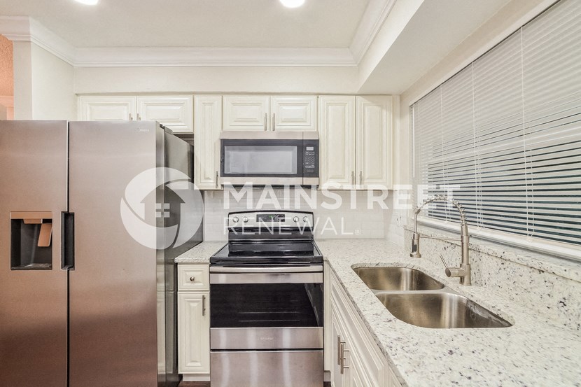 a renovated kitchen with granite countertops and stainless steel appliances