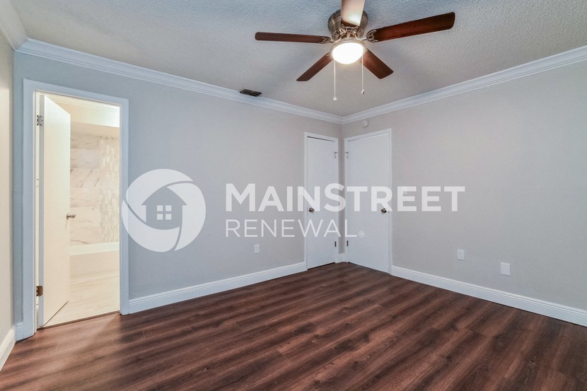 a living room with wood floors and a ceiling fan