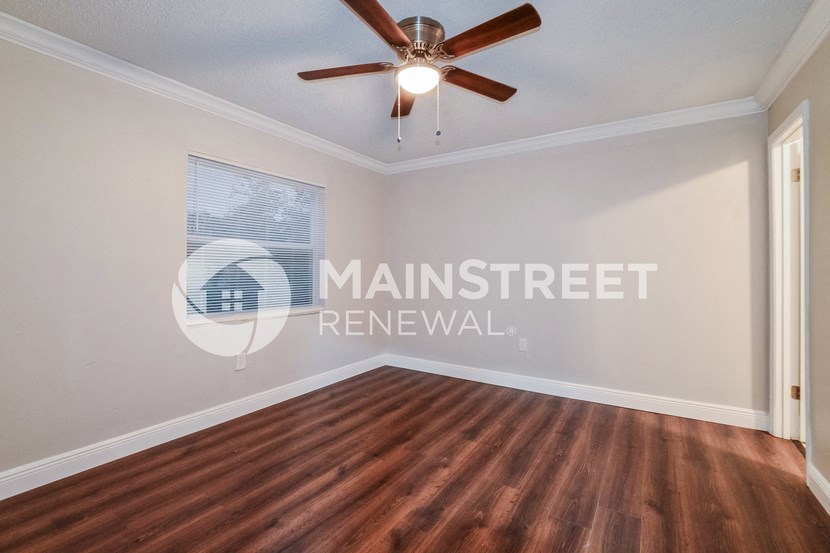 an empty living room with wood floors and a ceiling fan