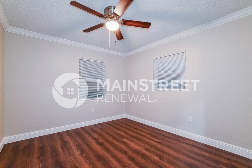 a bedroom with a hardwood floor and a ceiling fan