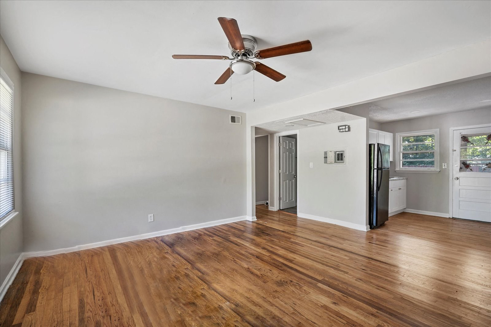 A room with a ceiling fan and wooden floors.