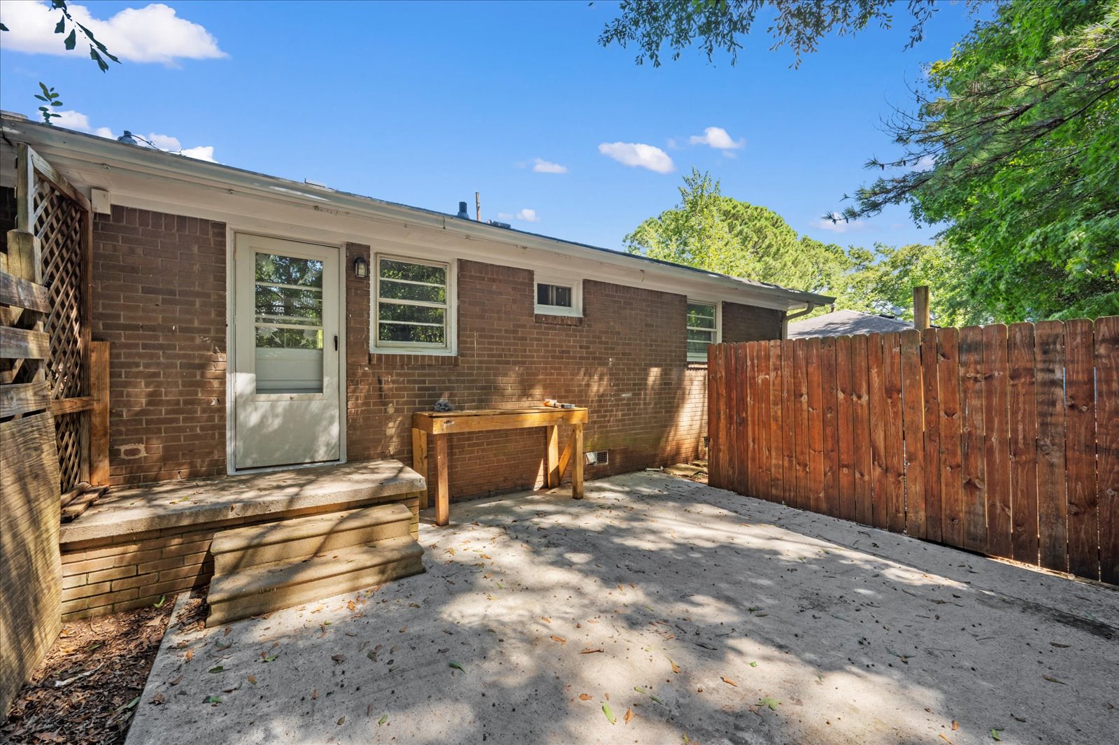 A backyard with a wooden fence and a brick house.