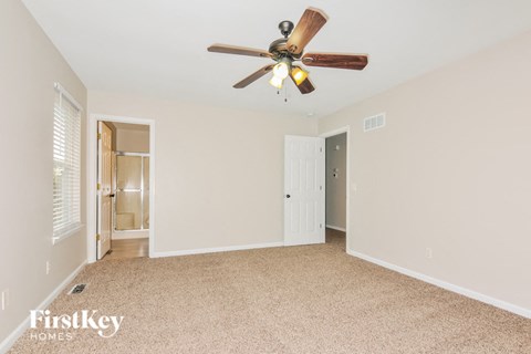 a bedroom with a ceiling fan and a door to a bathroom