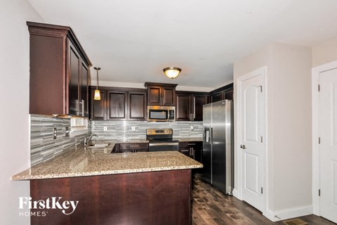 A kitchen with a granite counter top and wooden cabinets.