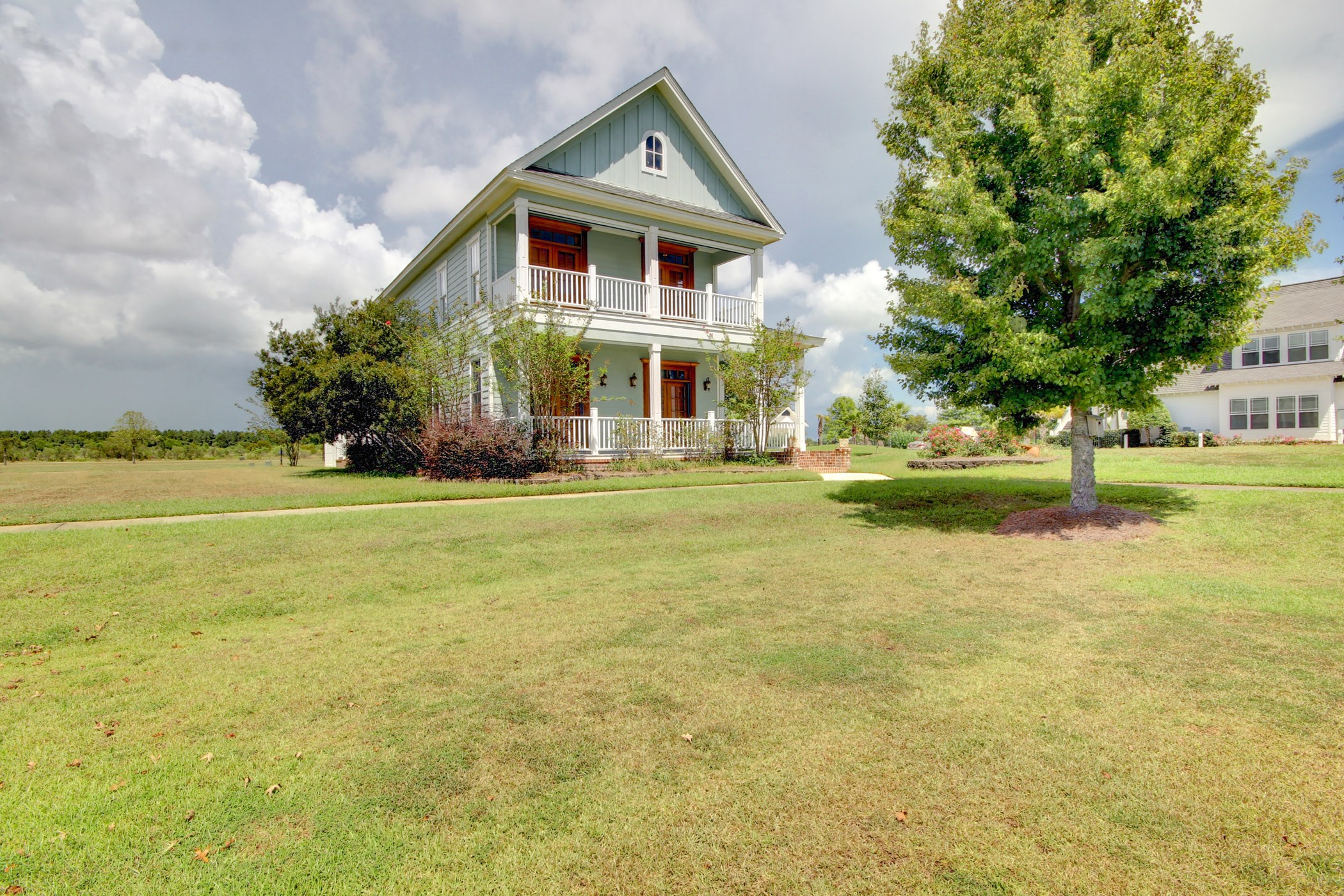 a house with a large lawn and a tree in front of it
